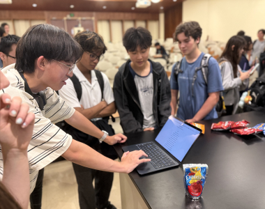 Students gather around a laptop