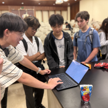 Students gather around a laptop