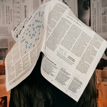 a person lays an open newspaper across their face